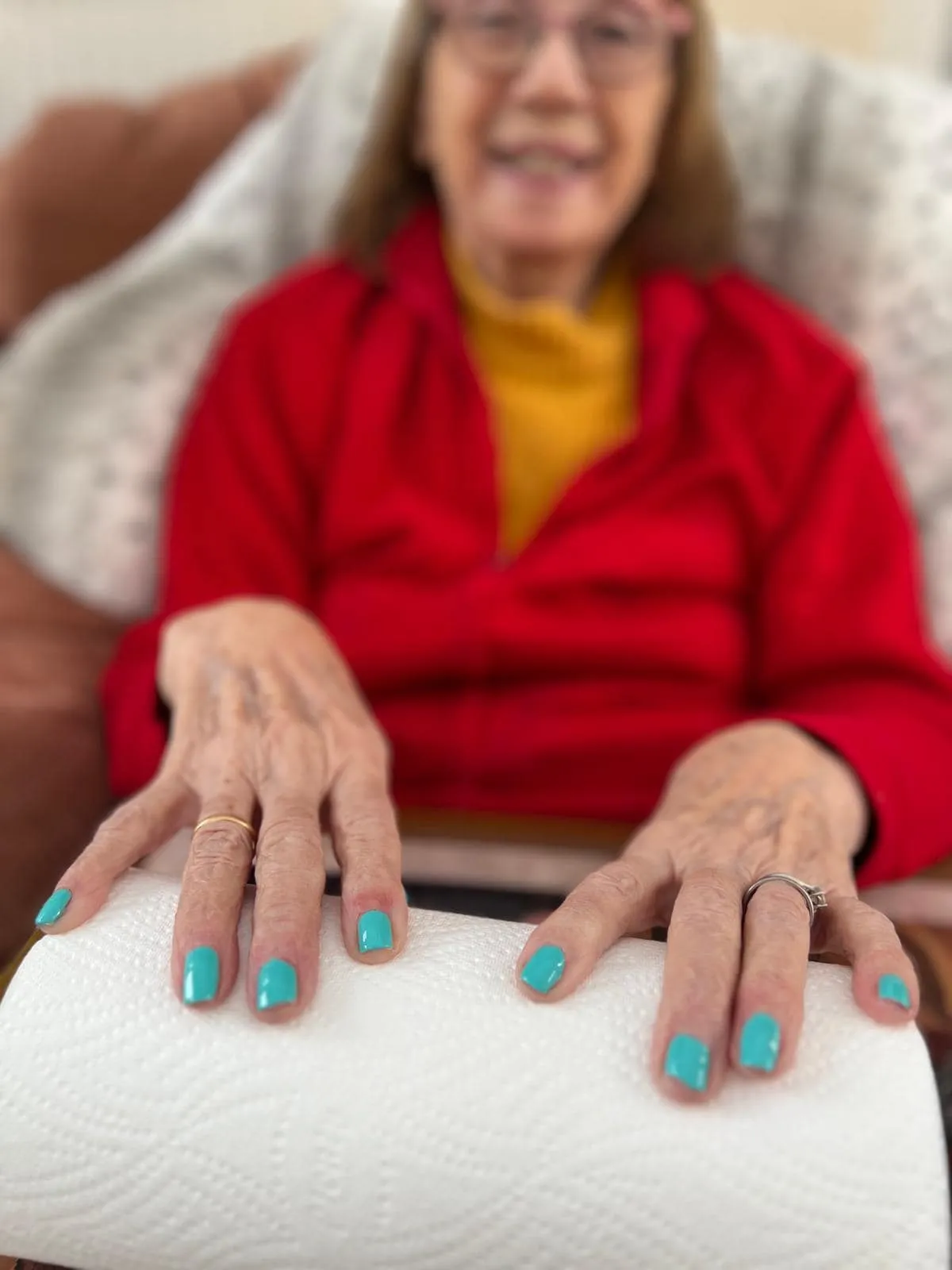 A woman sitting on a couch showing her painted nails.