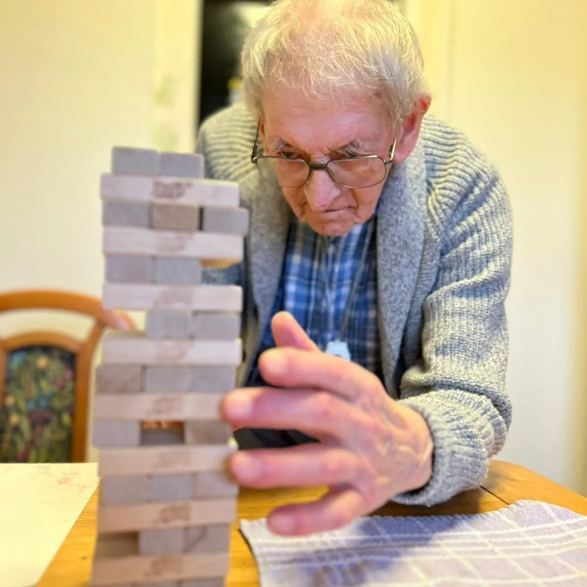 An older man playing with a tower of blocks.