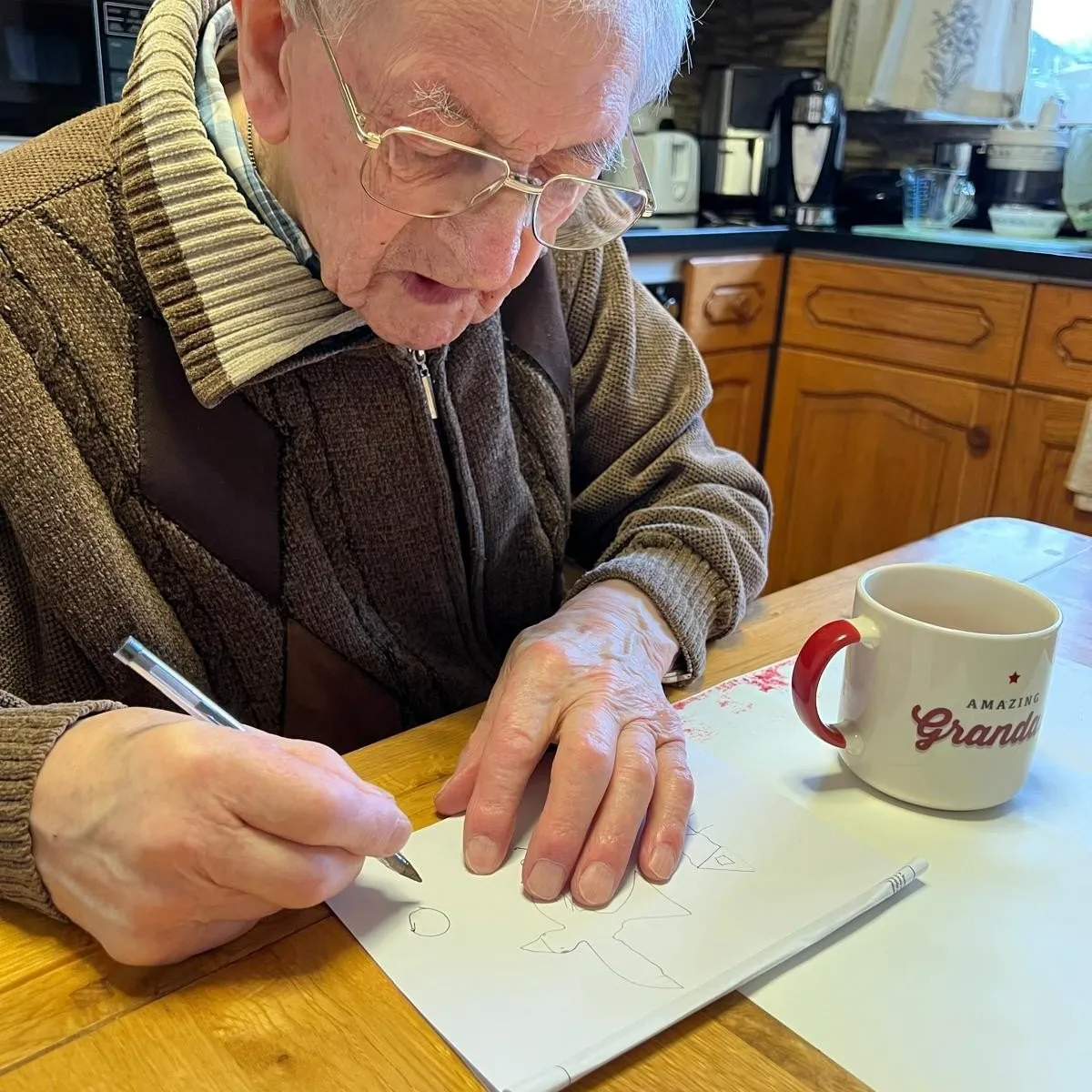 A man sitting at a table with a cup of coffee drawing.