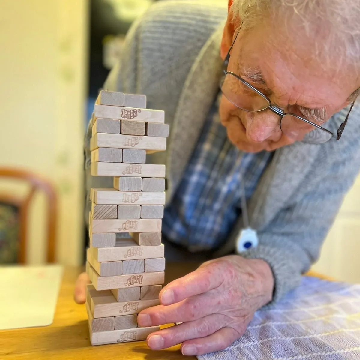 An older man playing with a wooden block tower.