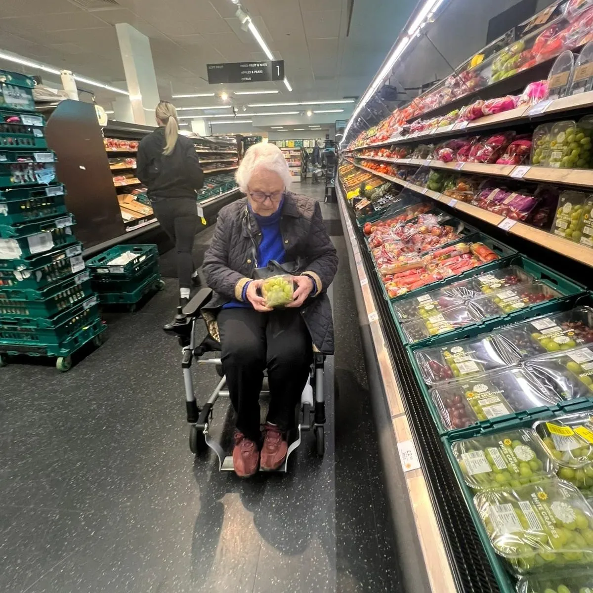 A woman sitting in a wheel chair in a grocery store.