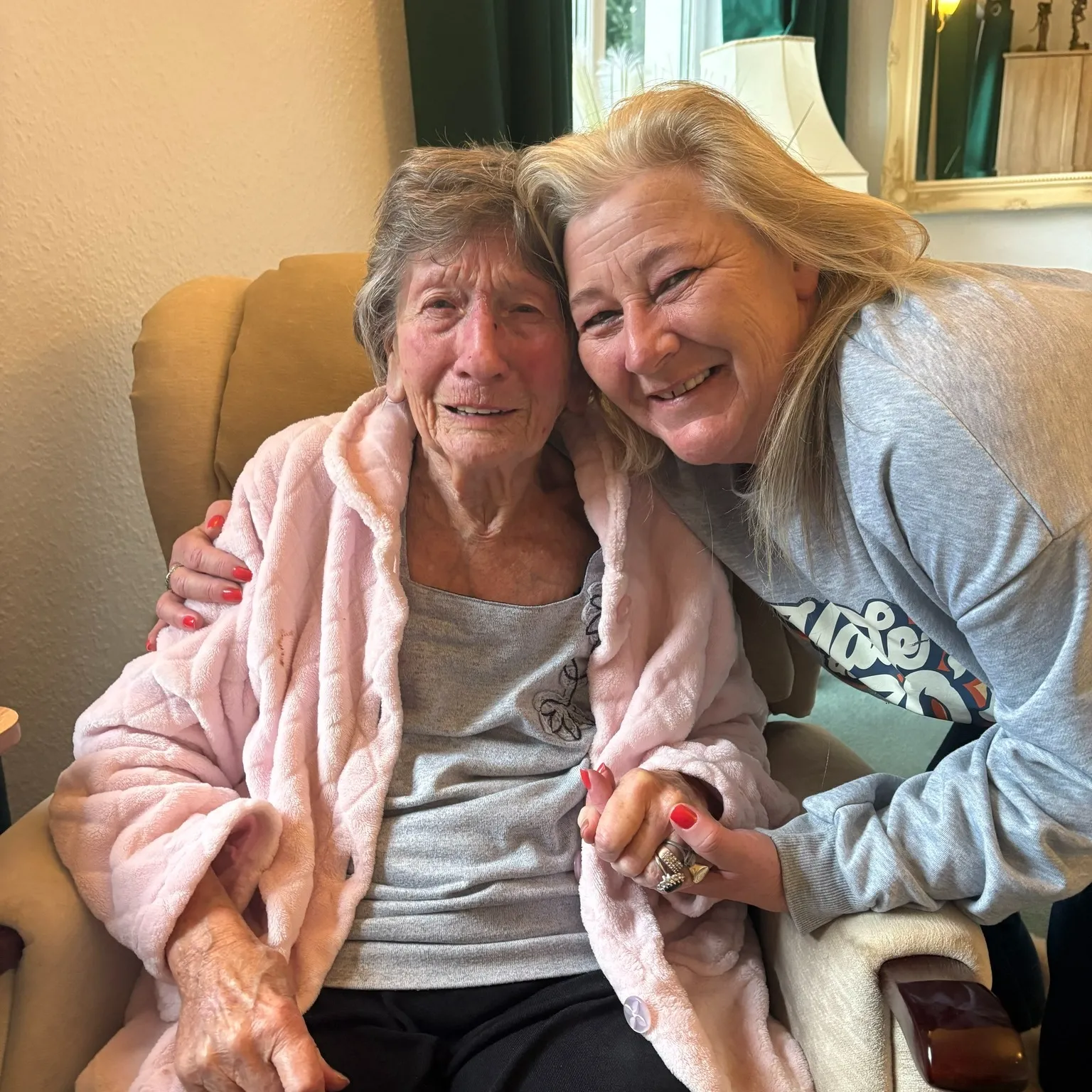 An older woman hugging a younger woman on a couch.