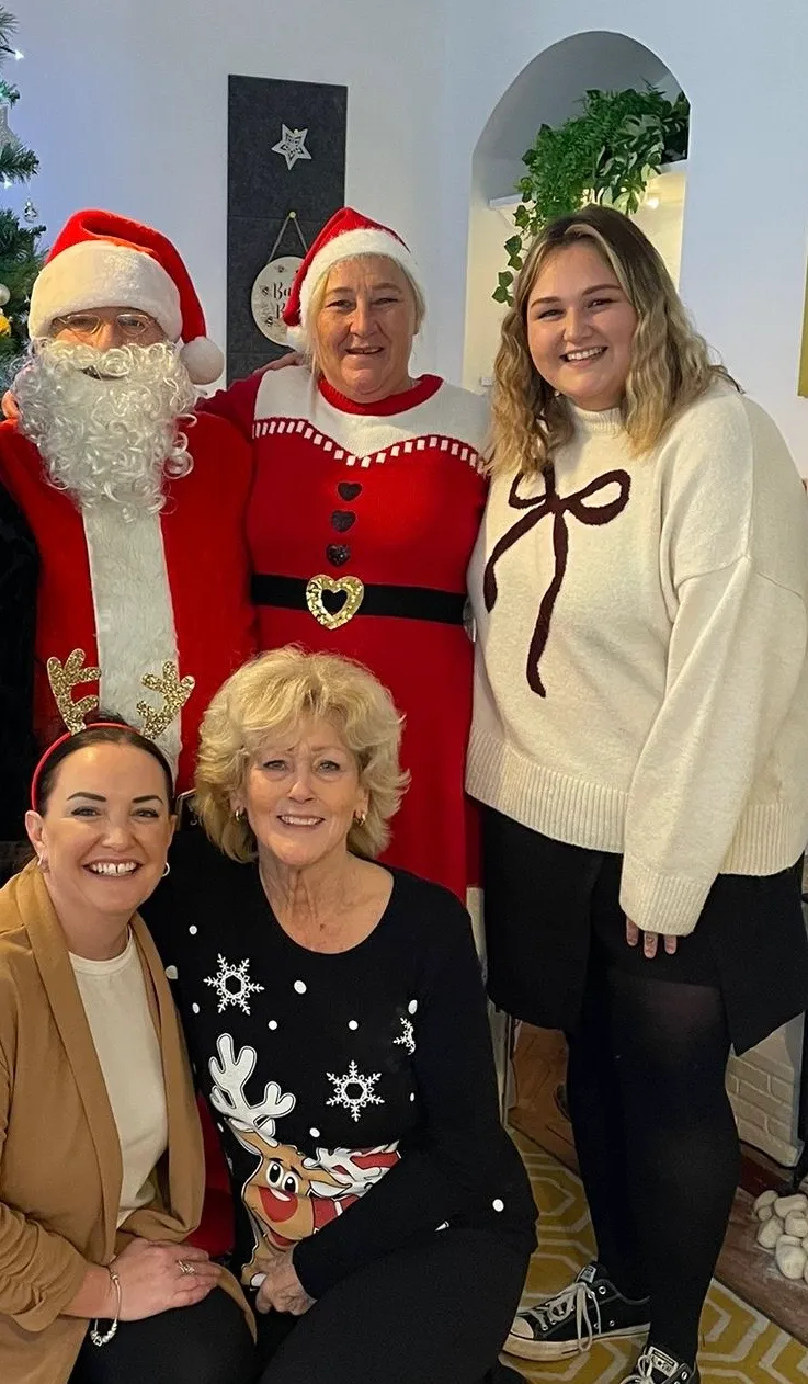 A group of people standing next to each other in front of a christmas tree.