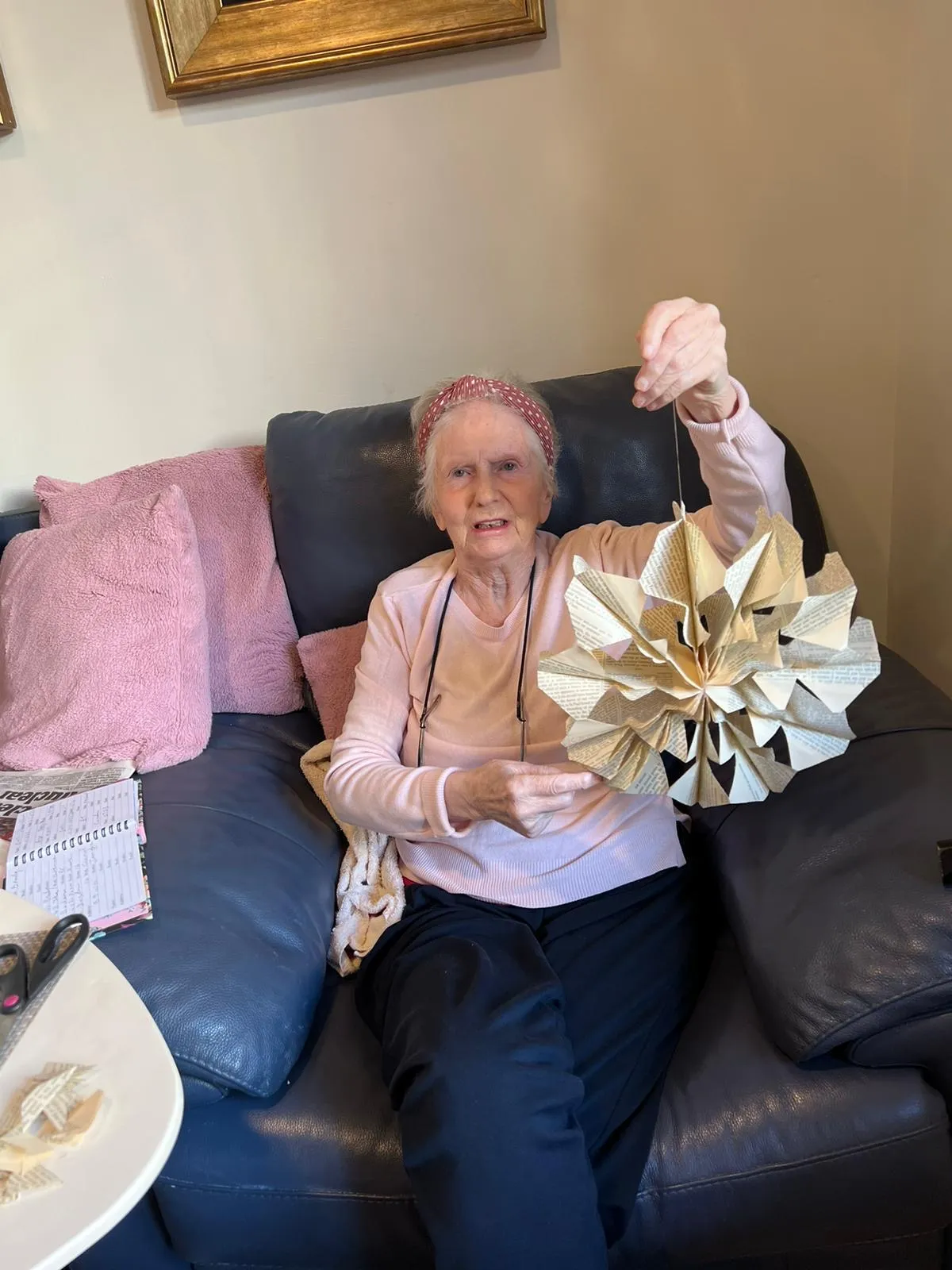 A woman sitting on a couch holding a paper flower.