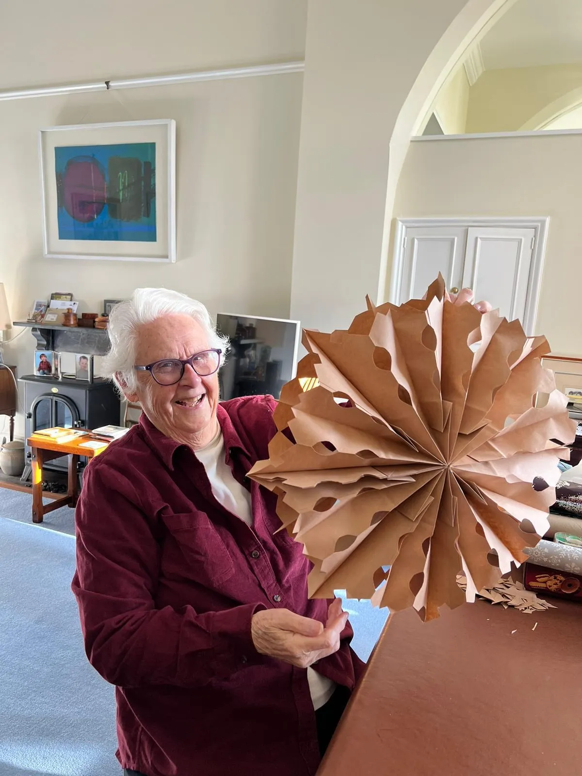 A woman holding a paper fan in a living room.