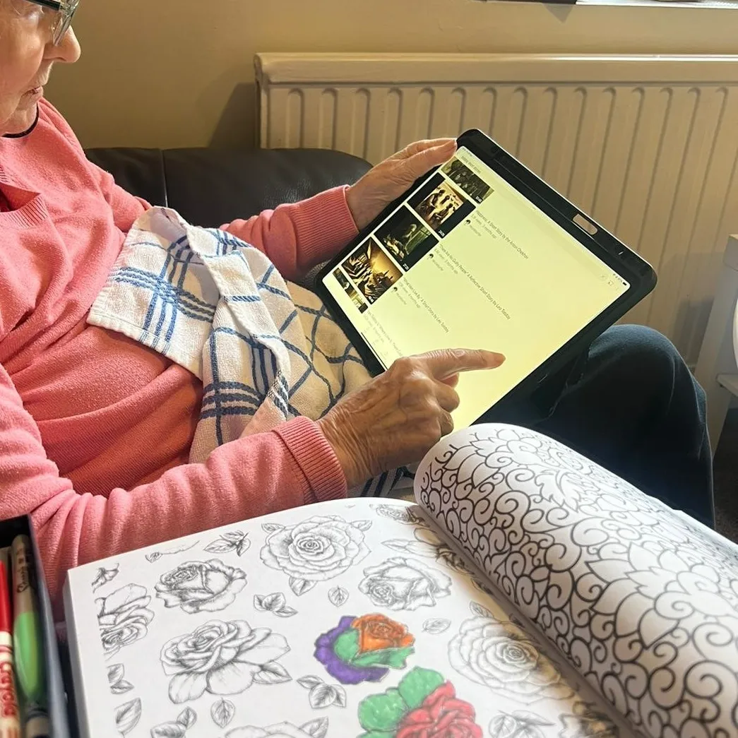 A woman sitting on a couch holding a tablet.