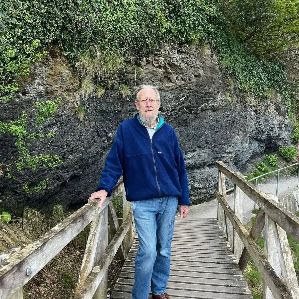 A man is standing on a wooden bridge.